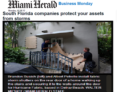 Brandon and Alby hanging hurricane fabric during an installation in South Florida